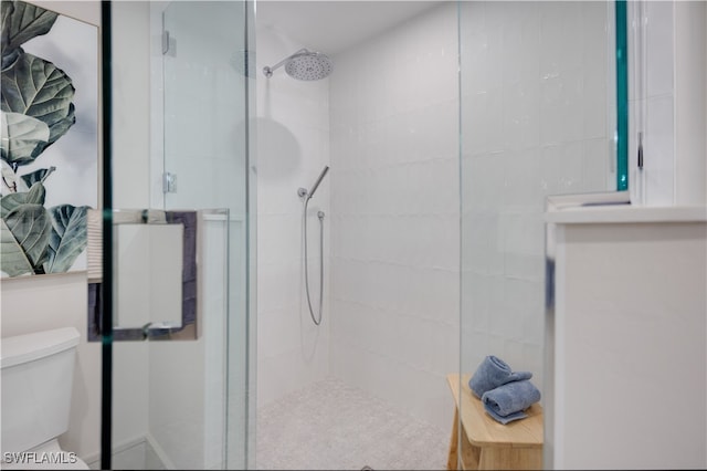 bathroom with a shower with door and toilet