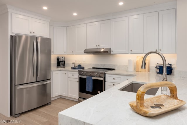 kitchen with light wood-type flooring, light stone countertops, stainless steel appliances, and white cabinetry