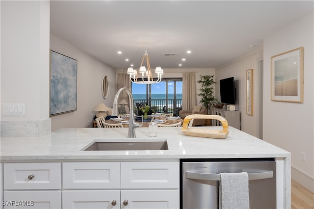 kitchen with a notable chandelier, light hardwood / wood-style flooring, dishwasher, light stone counters, and sink