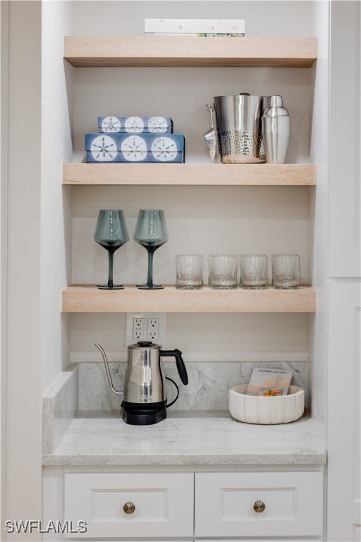 interior space with light stone counters and white cabinetry