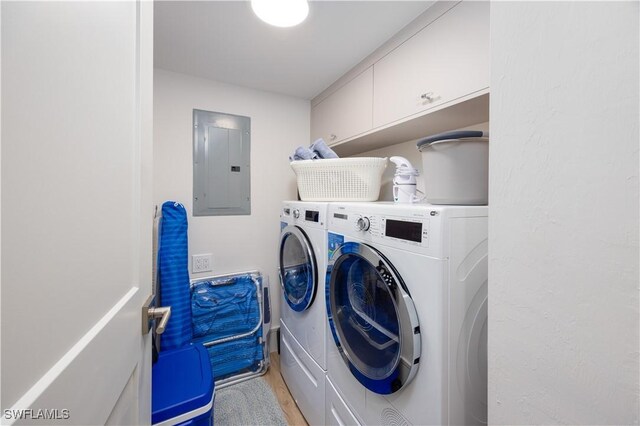 clothes washing area featuring cabinets, washing machine and clothes dryer, electric panel, and light hardwood / wood-style floors