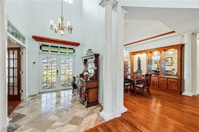 entrance foyer featuring decorative columns, french doors, ornamental molding, and a notable chandelier