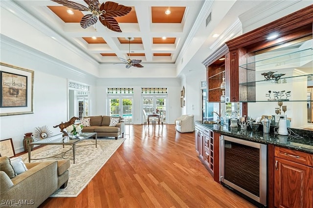 bar with ceiling fan, dark stone counters, coffered ceiling, beamed ceiling, and beverage cooler