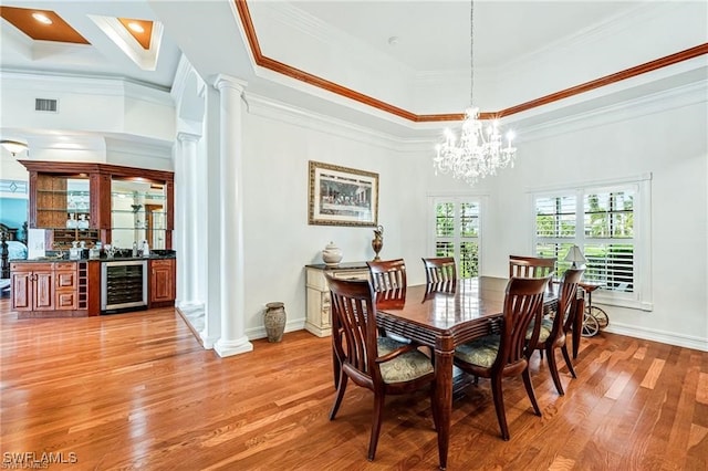 dining space featuring decorative columns, bar area, ornamental molding, and wine cooler