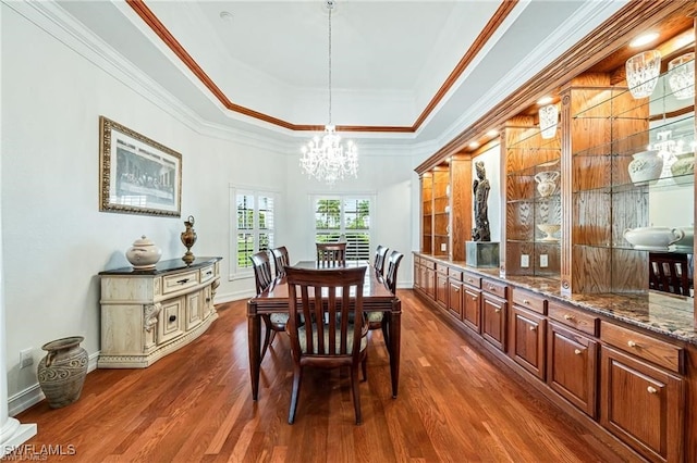 dining room featuring an inviting chandelier, crown molding, dark hardwood / wood-style flooring, and a tray ceiling