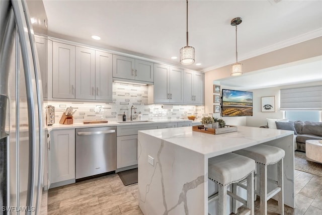 kitchen with sink, light stone counters, a center island, appliances with stainless steel finishes, and pendant lighting