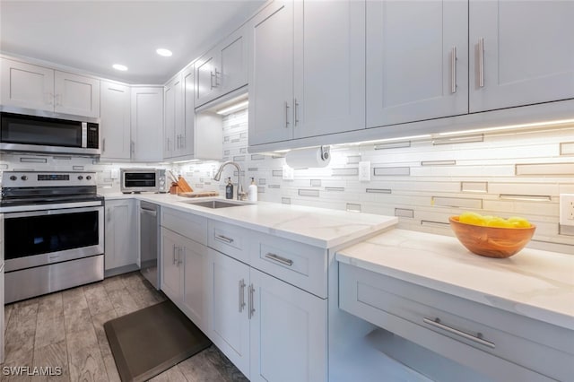 kitchen featuring white cabinetry, sink, light stone counters, and appliances with stainless steel finishes