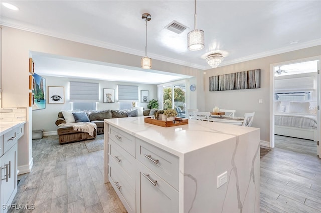 kitchen featuring decorative light fixtures, a center island, light hardwood / wood-style flooring, light stone countertops, and white cabinets