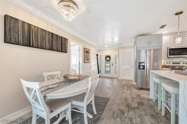 dining area with crown molding, light hardwood / wood-style floors, and a chandelier