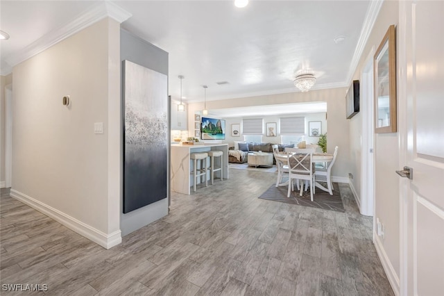 kitchen featuring hardwood / wood-style flooring, a kitchen breakfast bar, hanging light fixtures, and crown molding