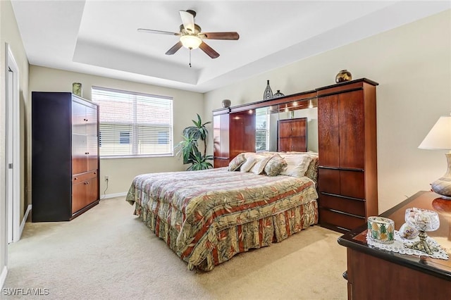 carpeted bedroom featuring a raised ceiling and ceiling fan