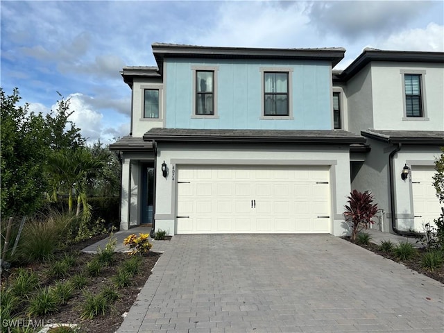 view of front facade with decorative driveway, an attached garage, and stucco siding