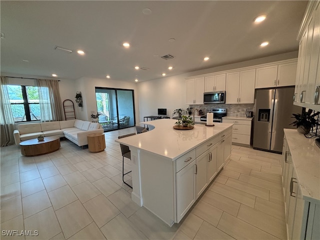 kitchen with white cabinetry, a center island, stainless steel appliances, and tasteful backsplash