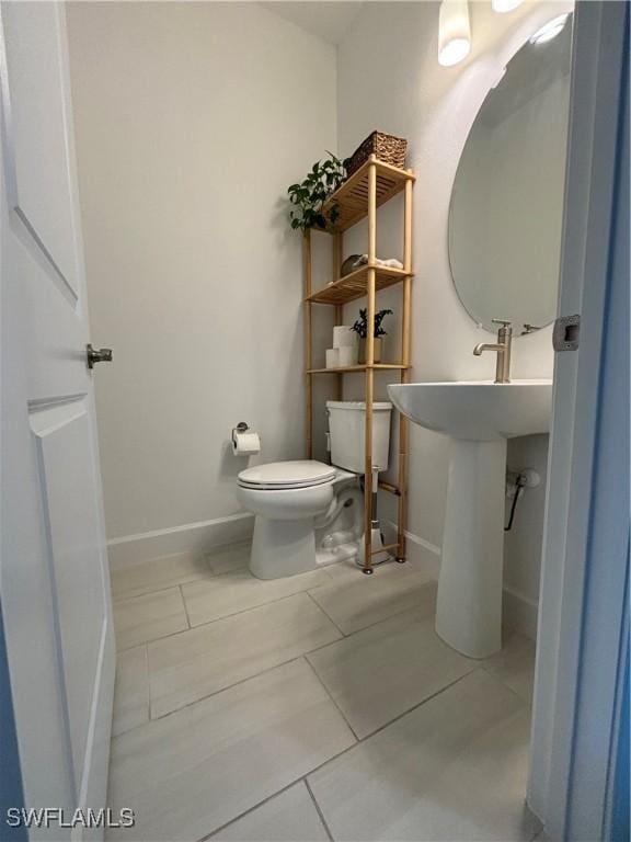 half bathroom featuring toilet, baseboards, and tile patterned floors