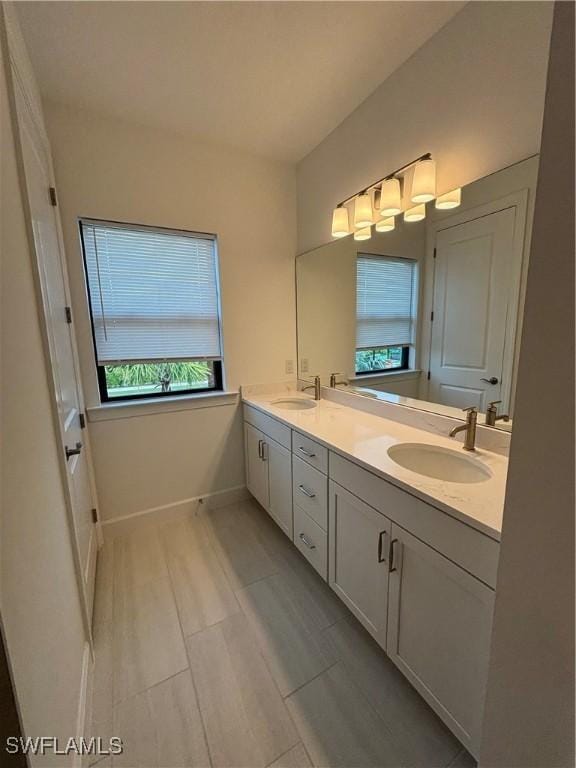 full bath featuring double vanity, a sink, and baseboards