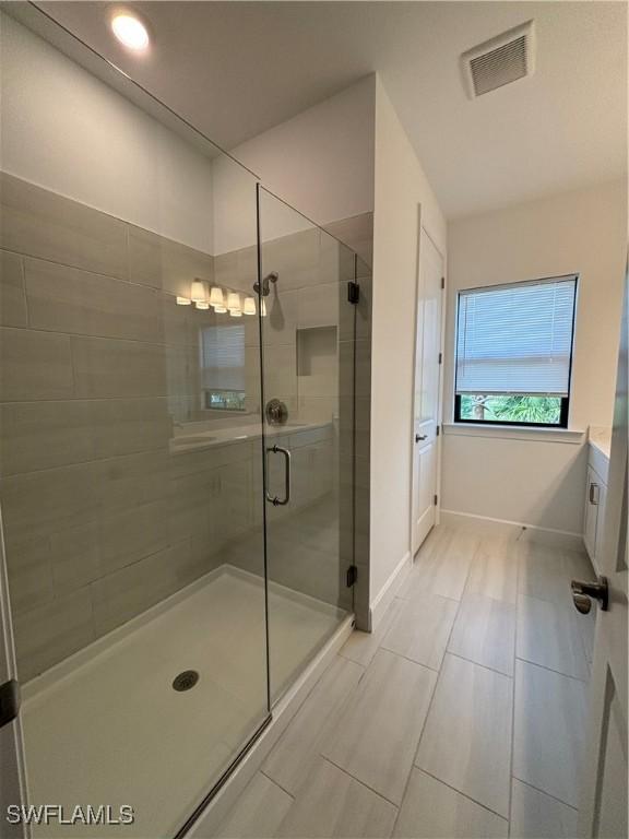 full bathroom with a shower stall, visible vents, and baseboards