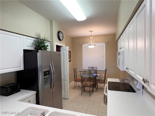 kitchen with white appliances, light tile patterned flooring, hanging light fixtures, and white cabinetry