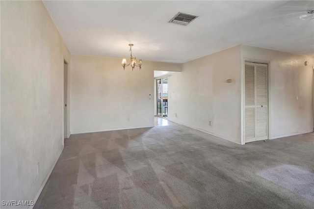 spare room with carpet and a chandelier