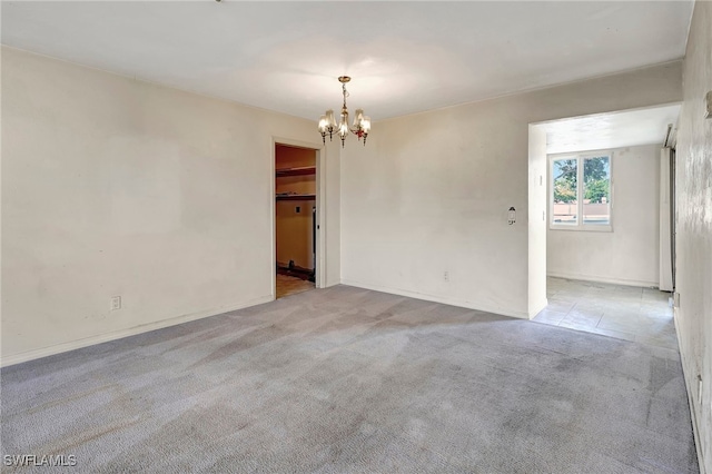 carpeted empty room with a notable chandelier