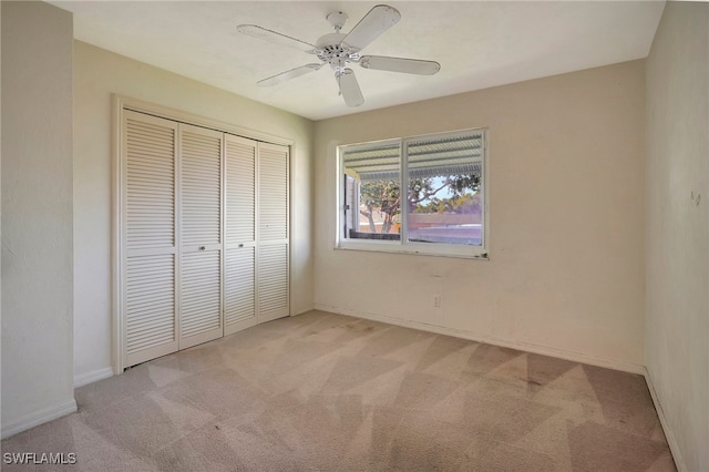 unfurnished bedroom with ceiling fan, a closet, and light carpet