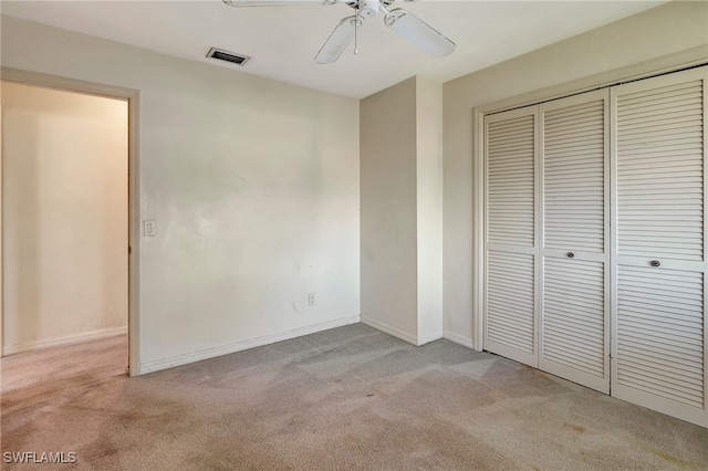 unfurnished bedroom with ceiling fan, light carpet, and a closet