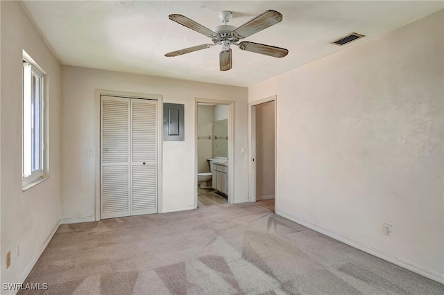 unfurnished bedroom featuring a closet, ceiling fan, light colored carpet, and ensuite bathroom