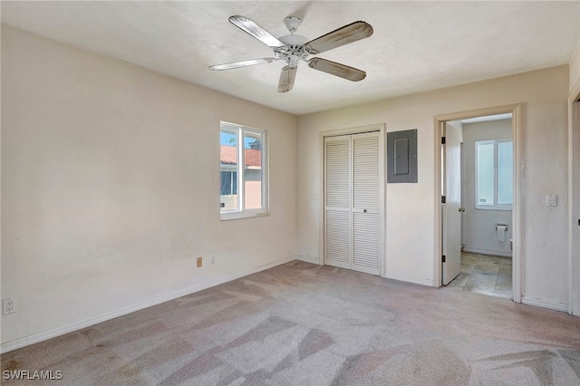 unfurnished bedroom featuring a closet, ceiling fan, electric panel, and light carpet