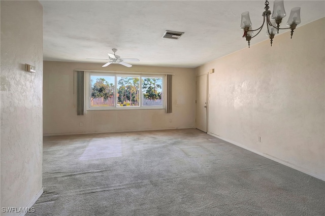 carpeted empty room featuring ceiling fan with notable chandelier