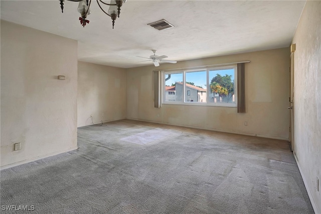 spare room featuring ceiling fan with notable chandelier and light colored carpet