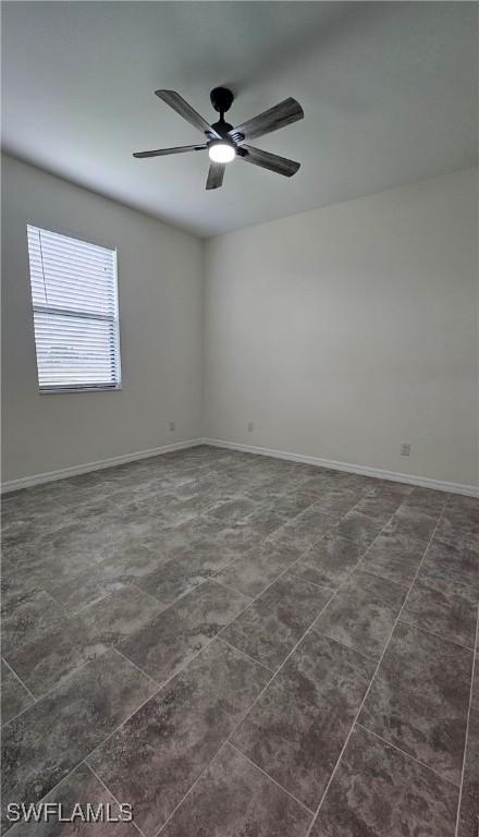 tiled spare room featuring ceiling fan