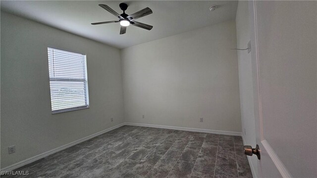 empty room featuring dark tile patterned flooring and ceiling fan