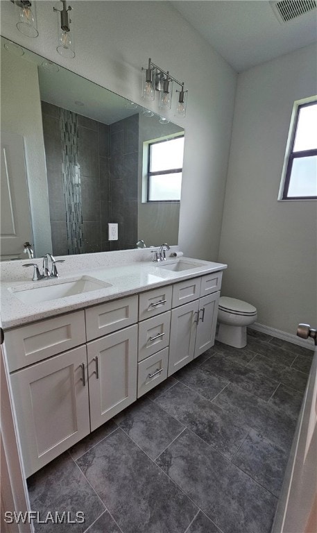 bathroom with plenty of natural light, double vanity, toilet, and tile patterned floors