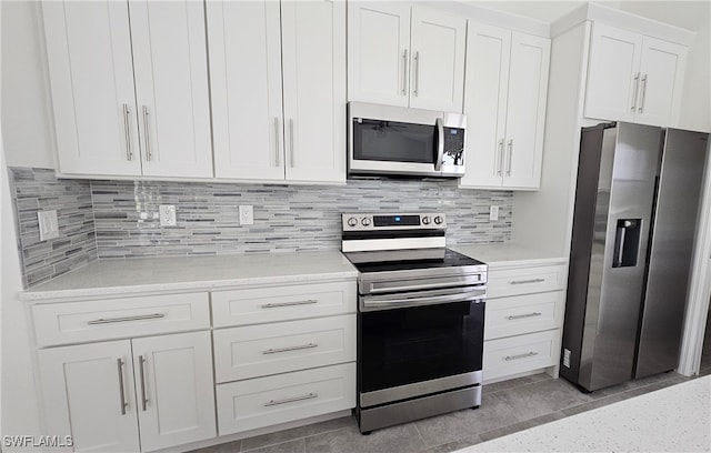 kitchen featuring tasteful backsplash, white cabinetry, light stone countertops, light tile patterned floors, and stainless steel appliances