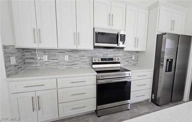 kitchen featuring white cabinetry, stainless steel appliances, light stone counters, and decorative backsplash