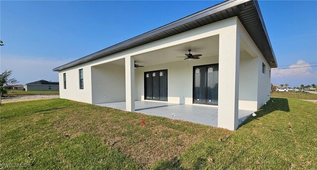 rear view of house with ceiling fan, a patio area, and a lawn