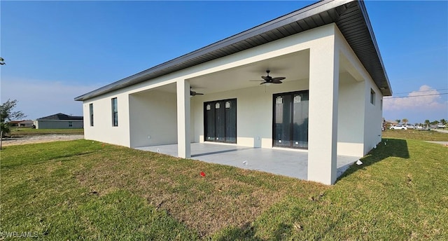 rear view of property with a yard, a patio area, and ceiling fan