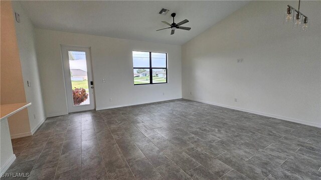 empty room featuring ceiling fan, lofted ceiling, and dark tile patterned floors