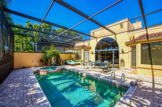 view of pool with glass enclosure, an in ground hot tub, and a patio