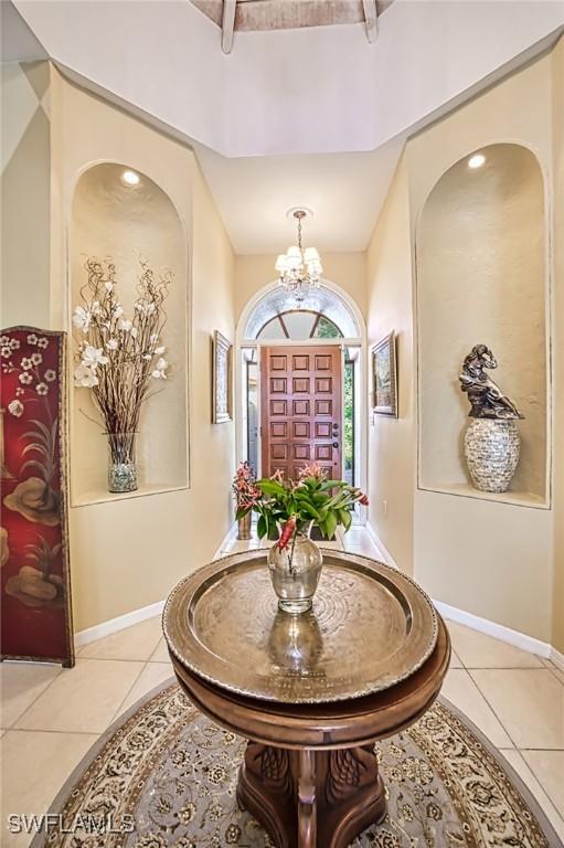 tiled entryway with a notable chandelier