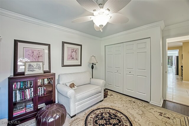 living area with crown molding, ceiling fan, and light hardwood / wood-style flooring