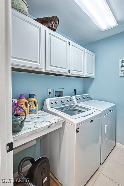 clothes washing area featuring cabinets, separate washer and dryer, and light tile patterned floors