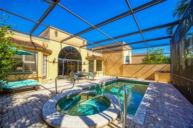 view of pool featuring an in ground hot tub, glass enclosure, and a patio area