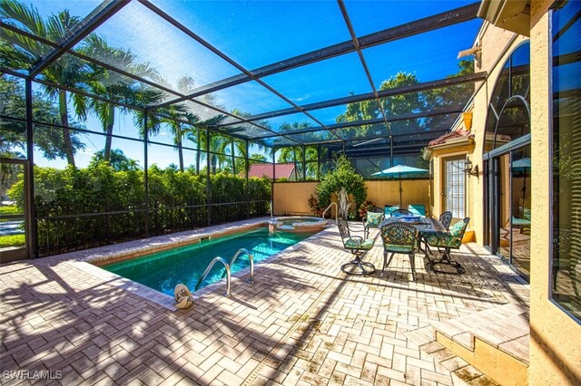 view of pool featuring an in ground hot tub, glass enclosure, and a patio area