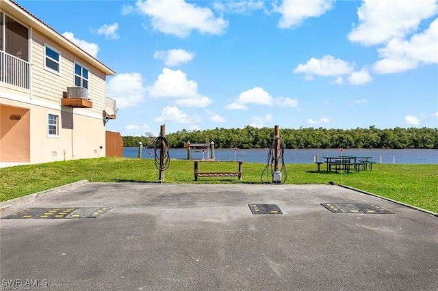 view of vehicle parking with a lawn and a water view