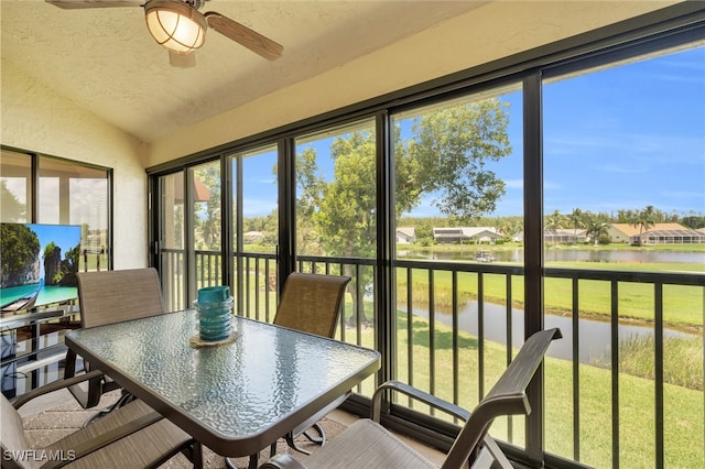 sunroom featuring ceiling fan, a water view, and lofted ceiling