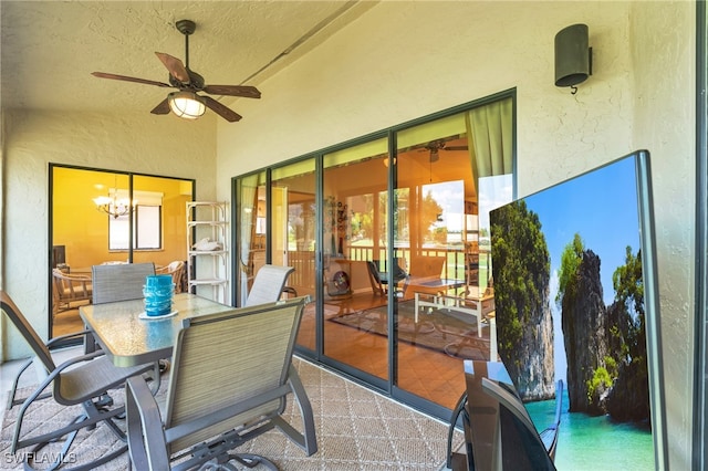 sunroom / solarium featuring ceiling fan with notable chandelier