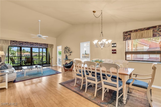 dining area featuring light wood-type flooring, high vaulted ceiling, and ceiling fan with notable chandelier