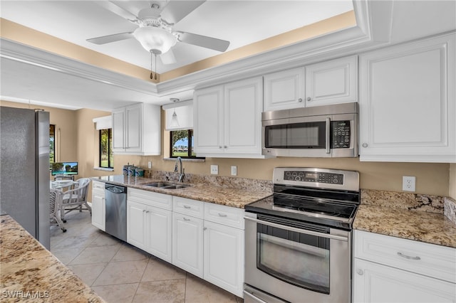 kitchen with ceiling fan, a tray ceiling, white cabinetry, appliances with stainless steel finishes, and light tile patterned floors