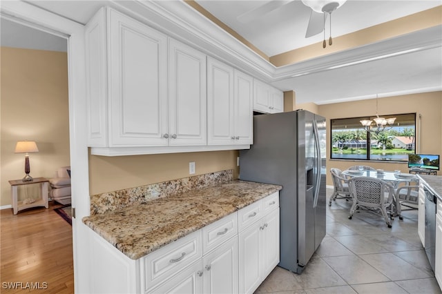 kitchen with light hardwood / wood-style flooring, light stone counters, ceiling fan with notable chandelier, white cabinets, and stainless steel fridge