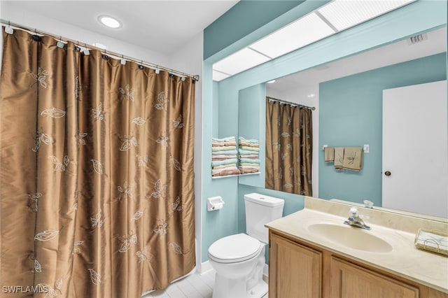 bathroom featuring tile patterned flooring, curtained shower, vanity, and toilet